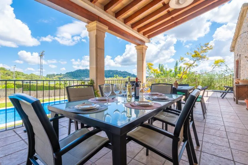 A covered outdoor dining area with a table and seating beside a pool.