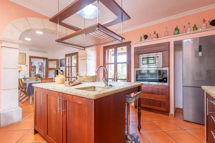 A spacious kitchen features a central island, built-in ovens, and stainless steel appliances.