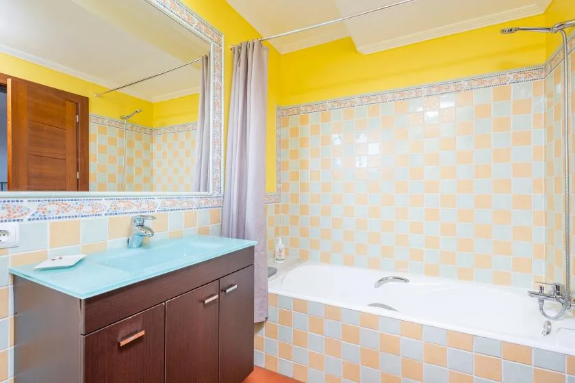 A bathroom with a bathtub, tiled walls, and a sink vanity.