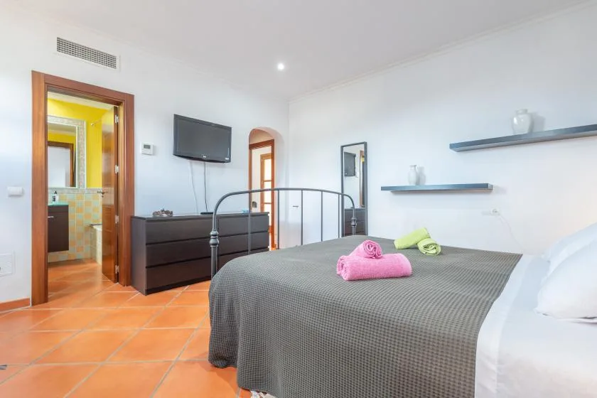 A bedroom with a double bed, dark dresser, and open doorway.