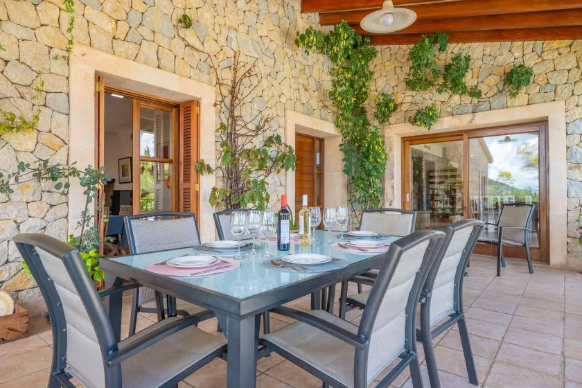 A stone-walled dining area with a set table and sliding glass doors.