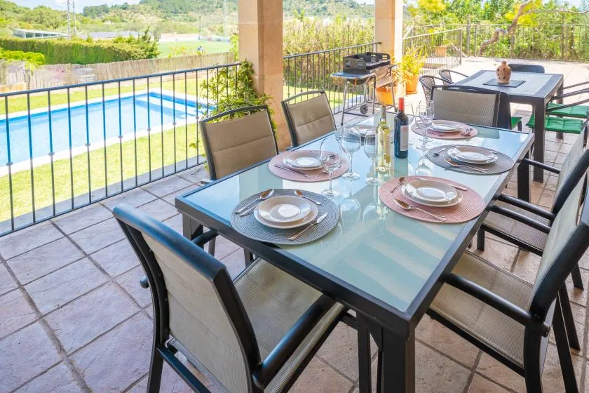An outdoor dining terrace with a set table and a pool nearby.