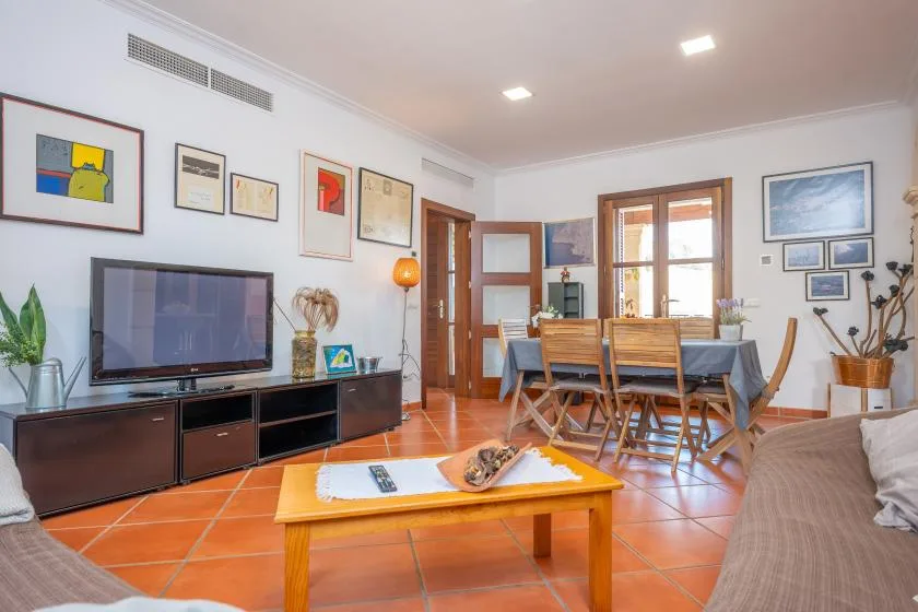 A living and dining room with a television, dining table, and wooden floor.