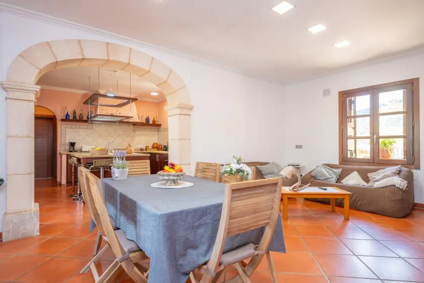 A dining and living area with a table, seating, and a kitchen beyond.