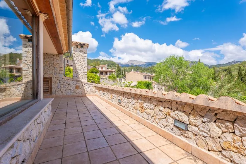 A tiled outdoor terrace overlooks a stone wall and green hills.