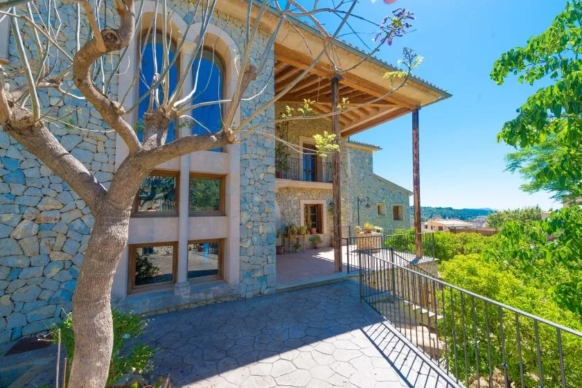 A stone house exterior with a covered patio and a view of the surrounding greenery.