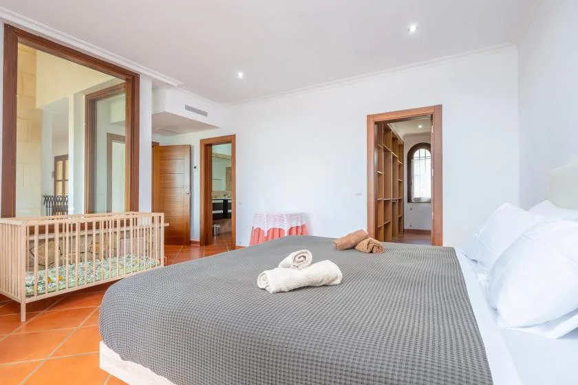 A bedroom with a large bed and a wooden crib beside it.