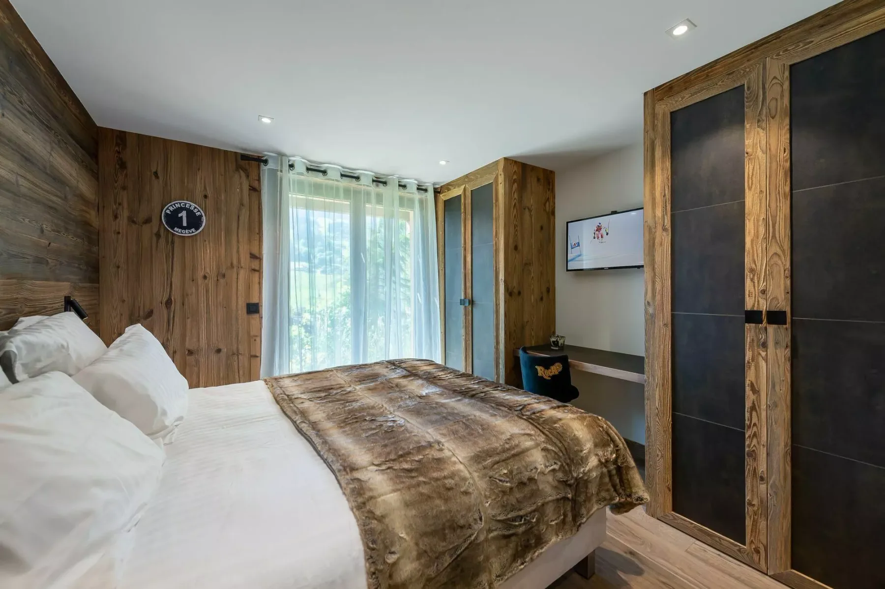 A bedroom with a bed, wood-paneled walls, and a curtained window.