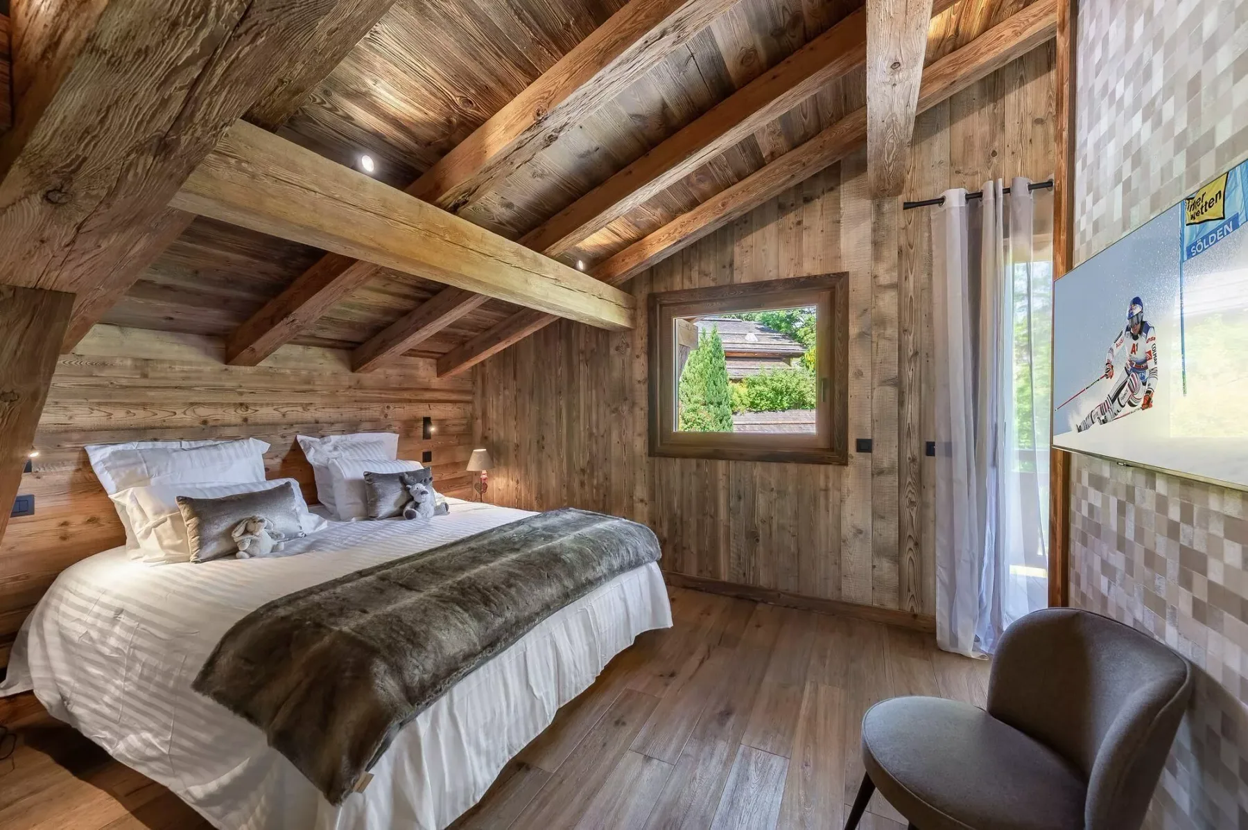 A rustic bedroom with a bed beneath exposed wooden beams and a window.