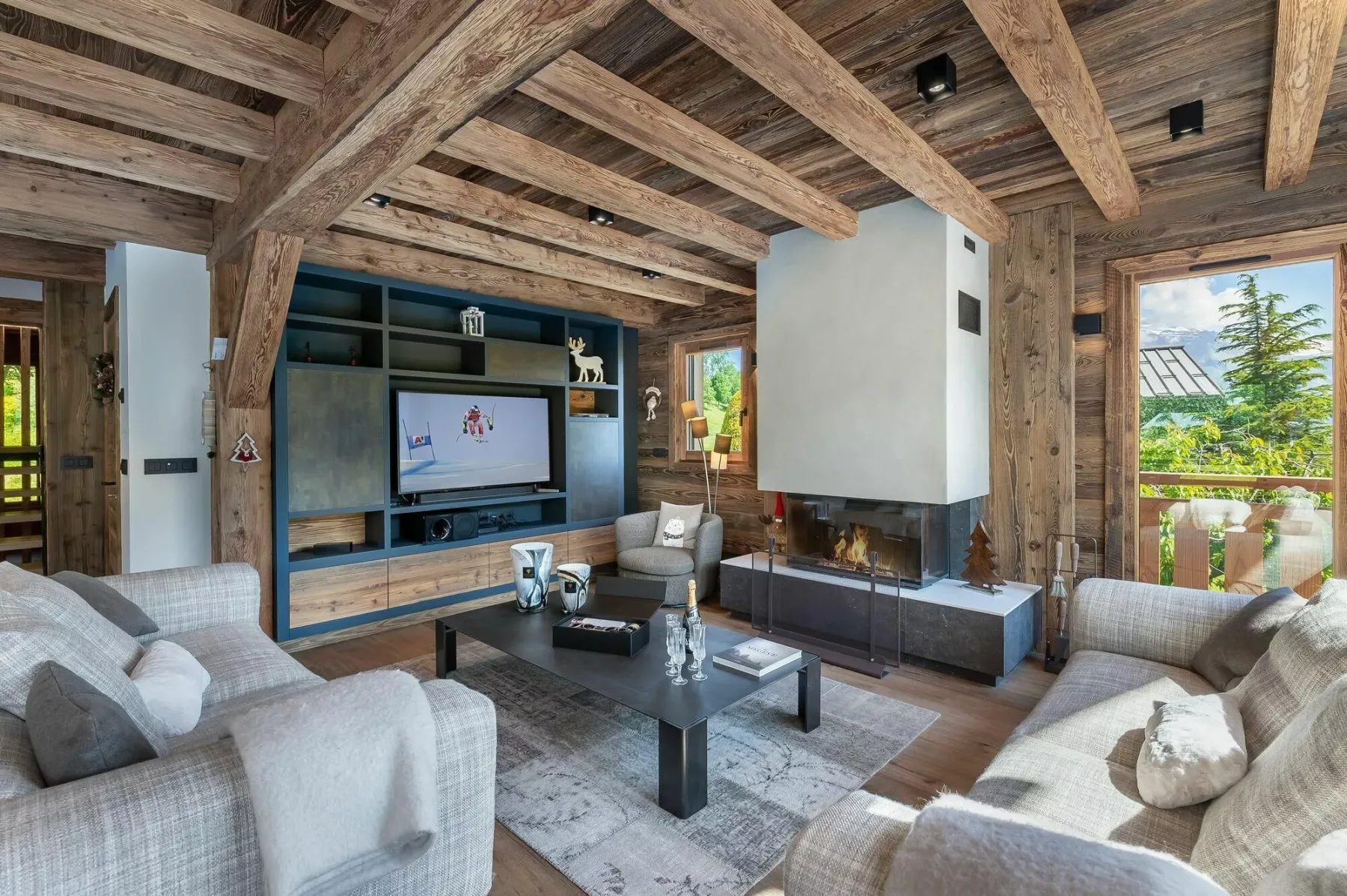 Una sala rústica con vigas de madera expuestas, asientos y un televisor.