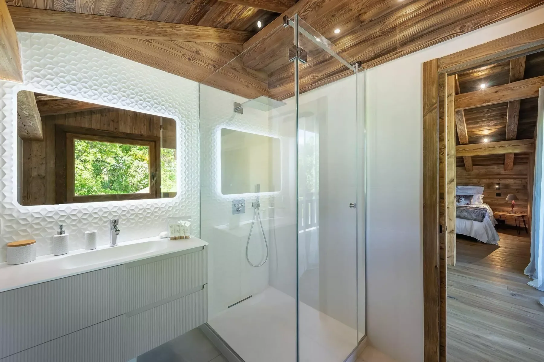 A bright bathroom with a glass shower and a wide mirror above the vanity.