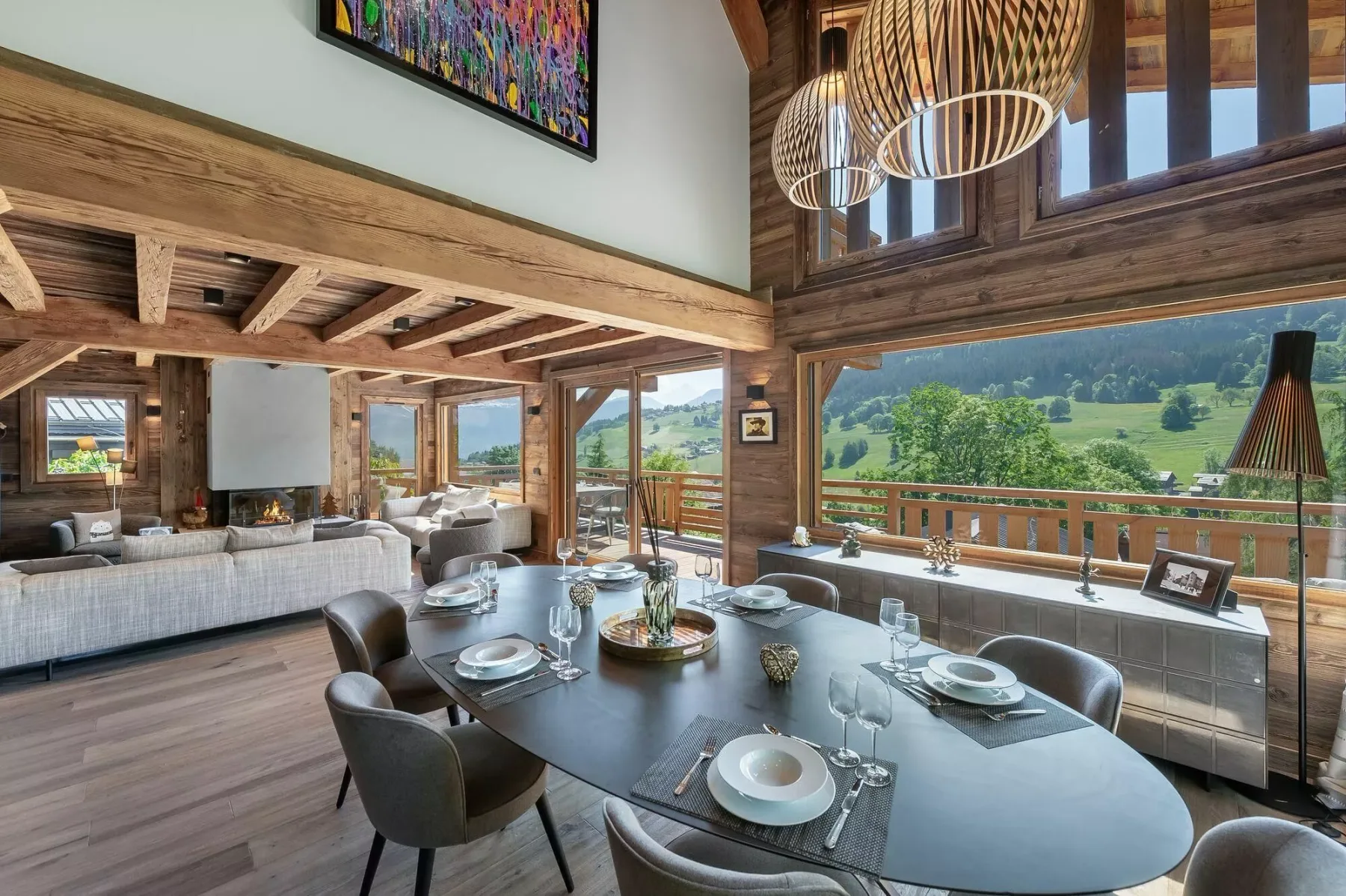 A dining area with a set table, large windows, and a view of green hills.
