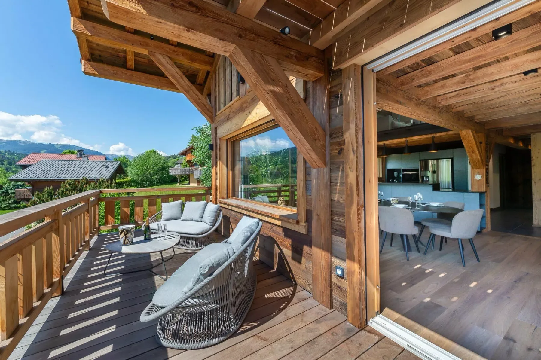 A wooden deck with outdoor seating opens onto a dining area.
