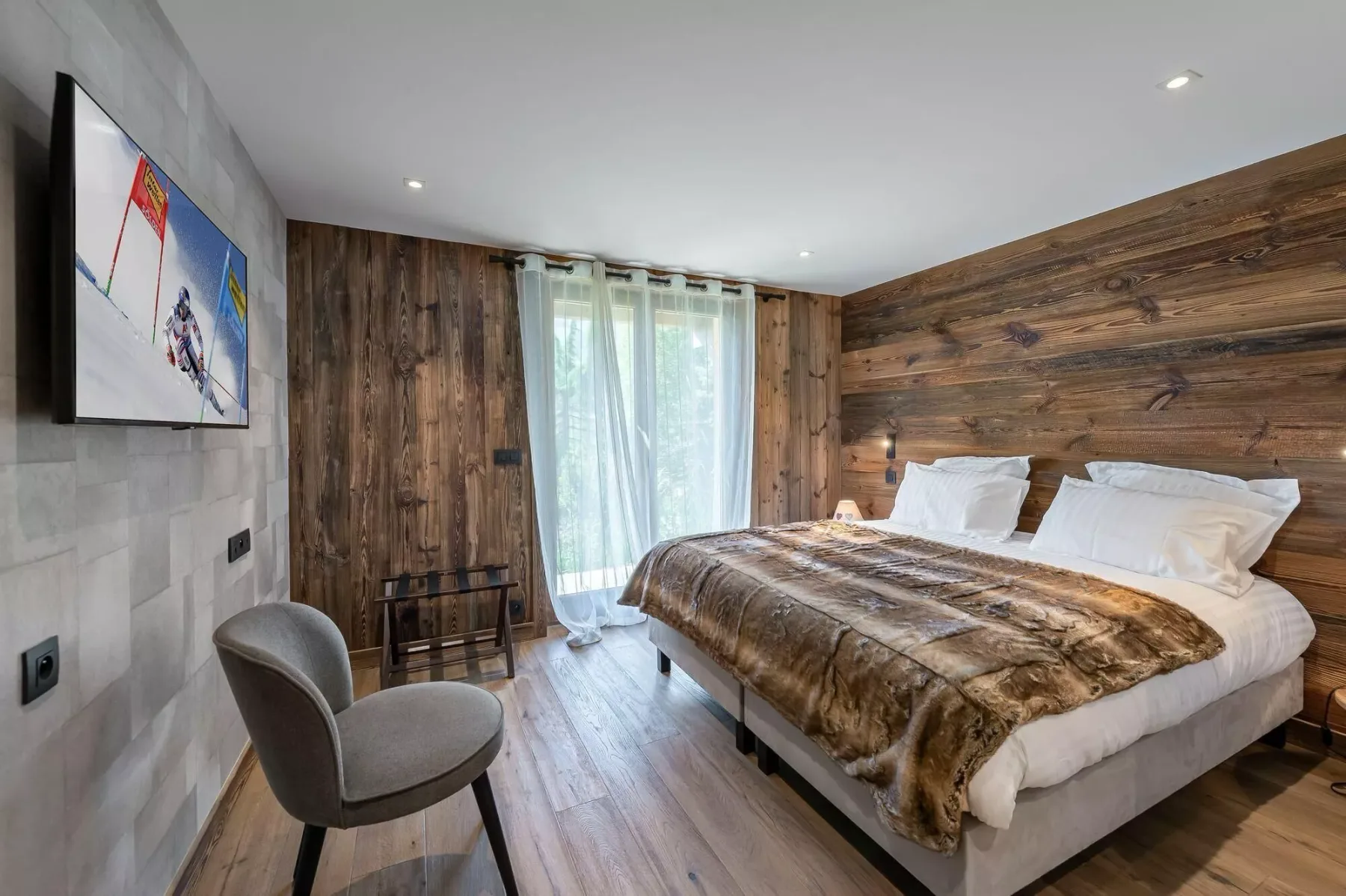 Bedroom with a large bed beside a window with sheer curtains.