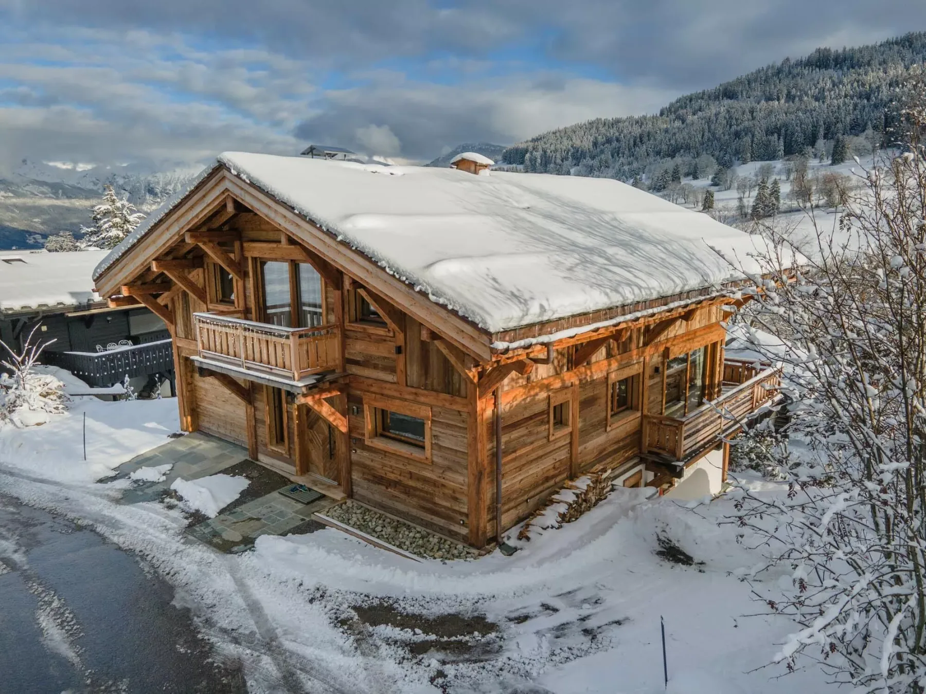 A wooden chalet stands in a snowy landscape beneath a cloudy sky.
