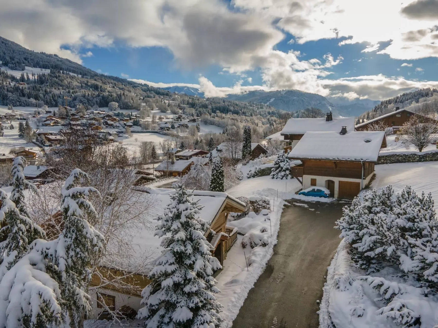 A snowy mountain village spreads across the valley beneath a cloudy sky.