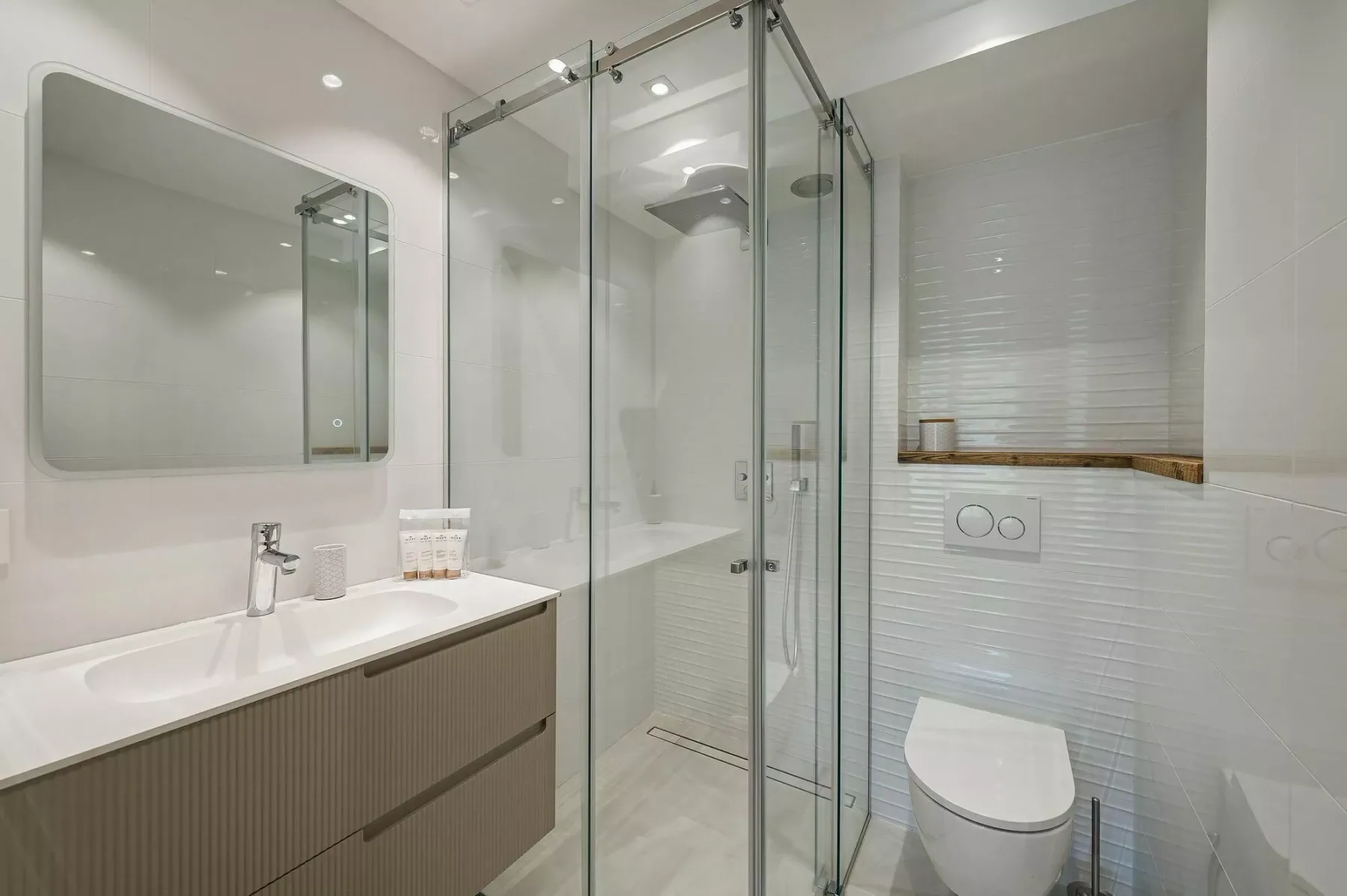 A modern bathroom with a glass shower, vanity, and toilet.