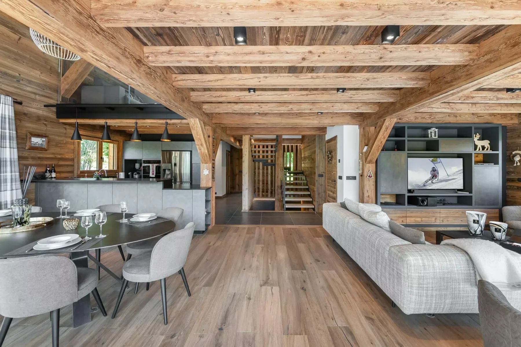 Sala-comedor de planta abierta con cocina y vigas de madera expuestas.