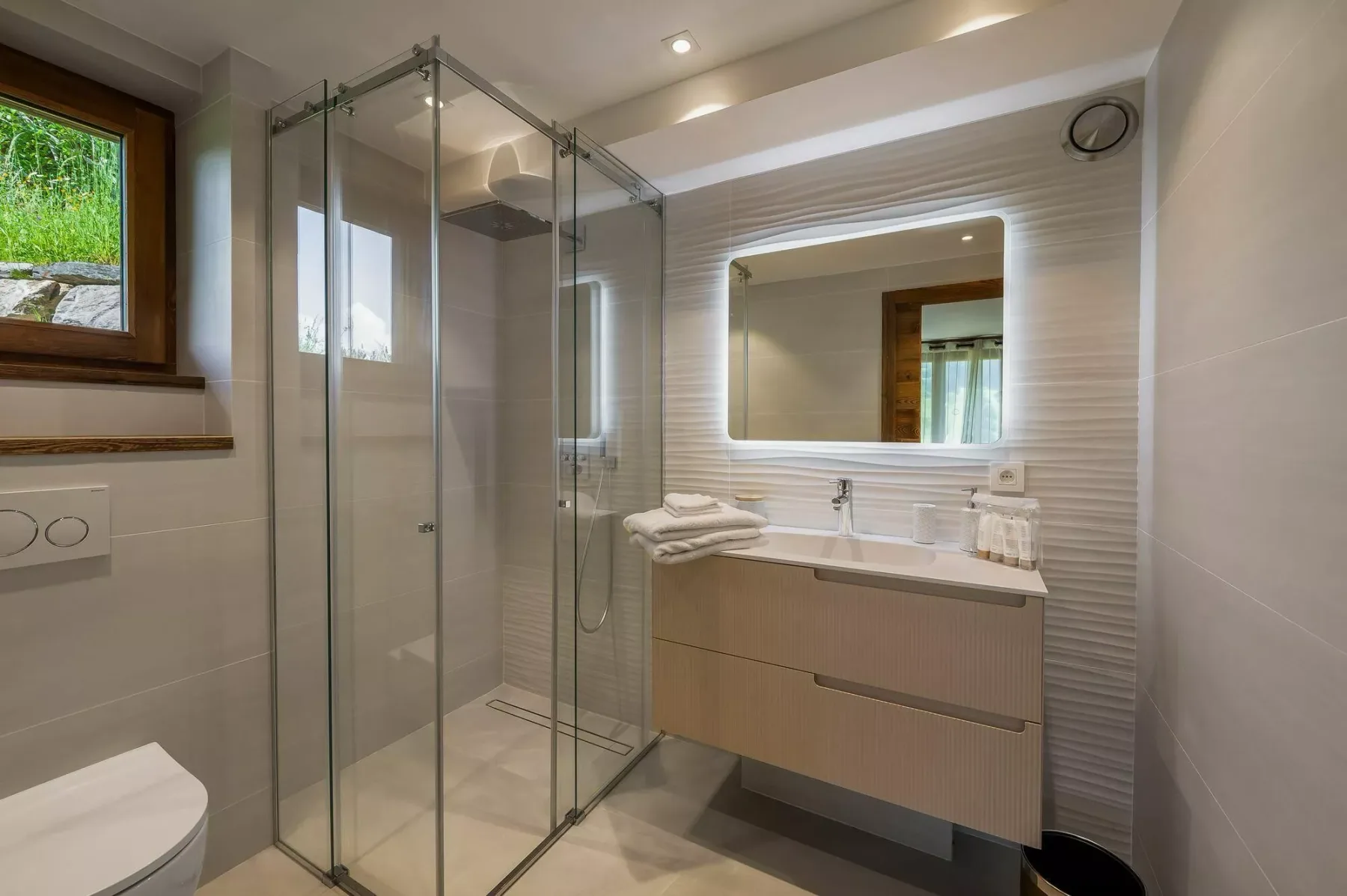 A bright bathroom with a glass shower and a sink beneath a mirror.