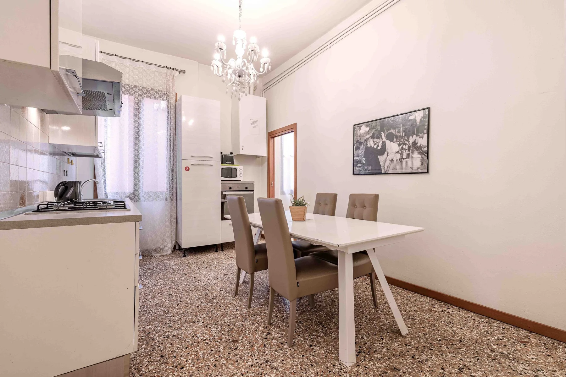 A bright kitchen and dining area with a table, chairs, and chandelier.