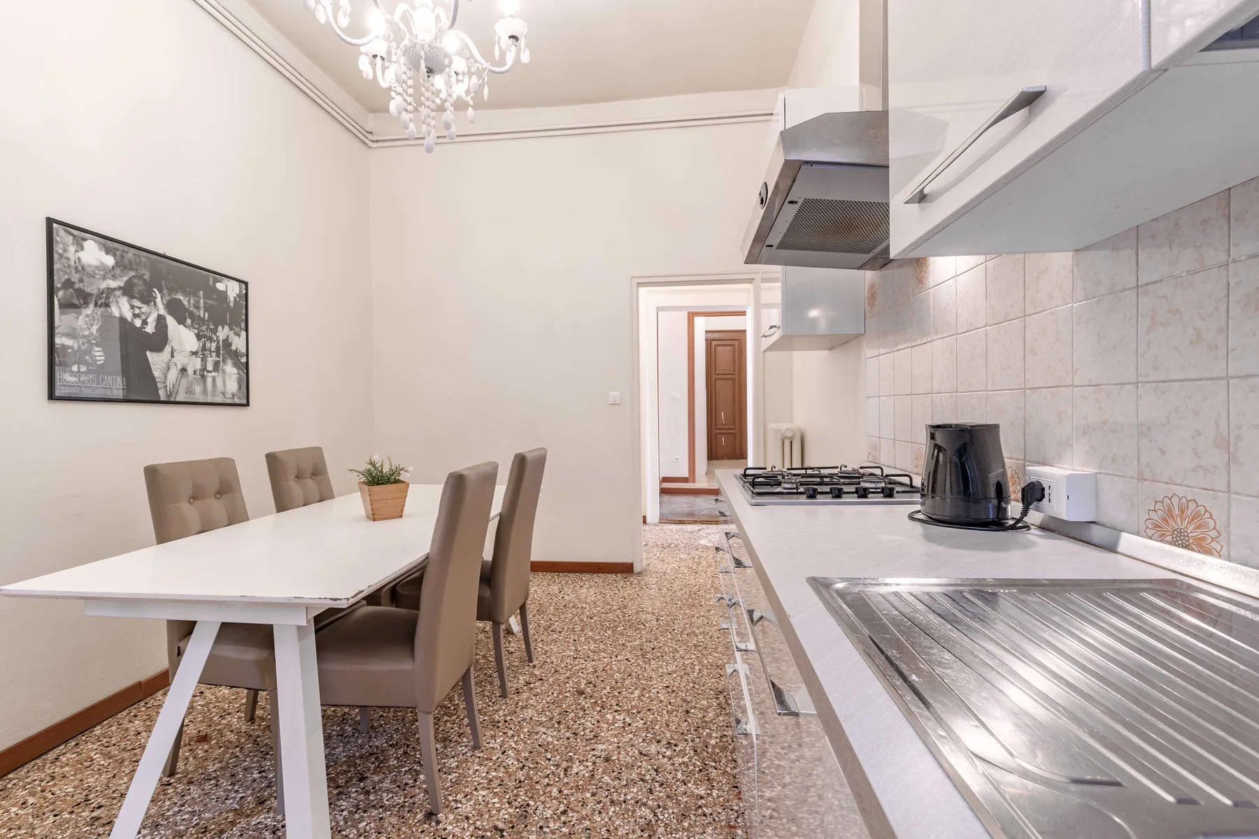 A dining area beside a kitchen counter, with a table, seating, and a sink.