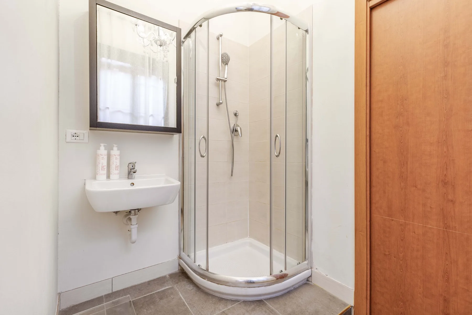 A bathroom with a glass shower and a wall-mounted sink.