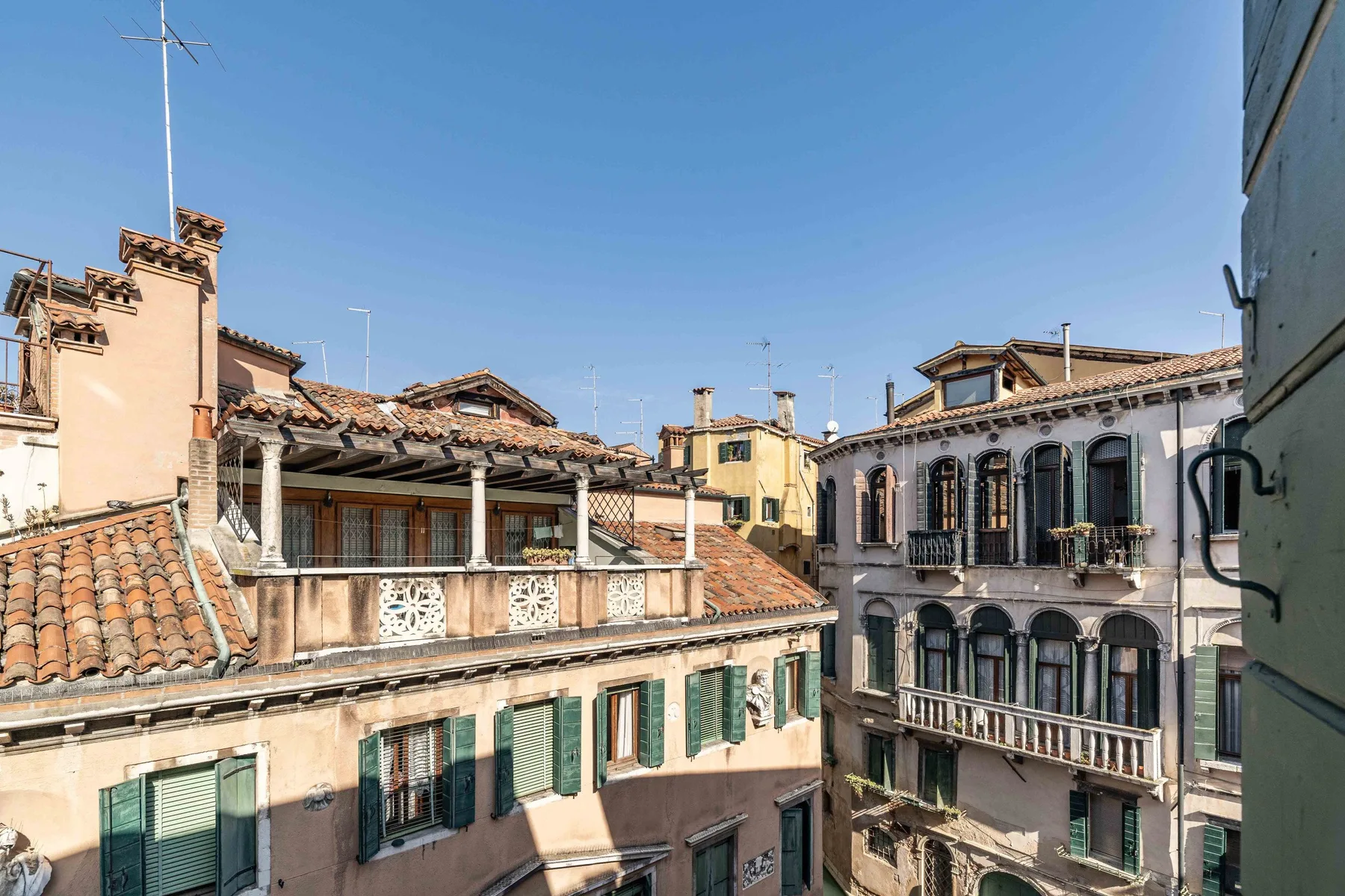 Rooftops and neighboring buildings line a sunny urban street beneath a clear sky.
