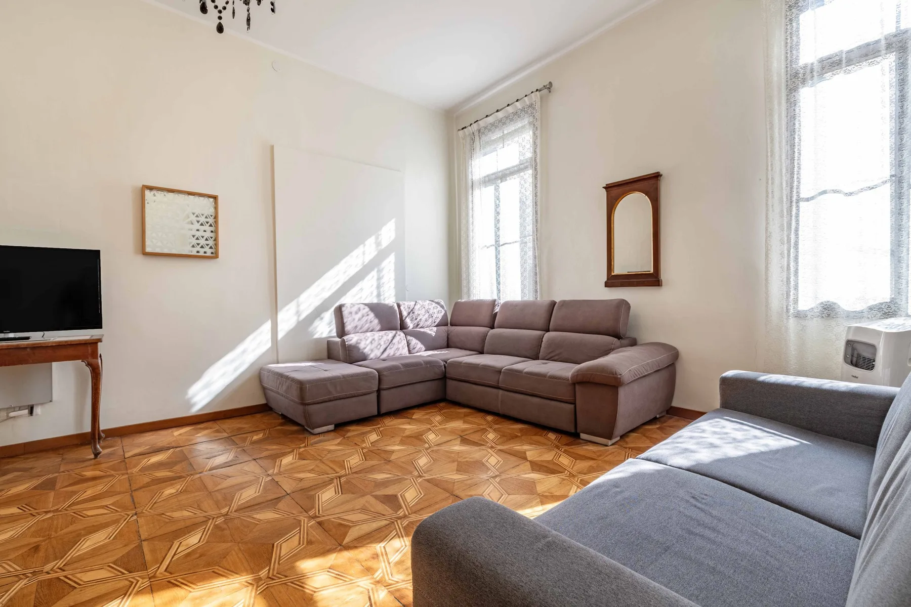A bright living room with sectional seating and tall windows.