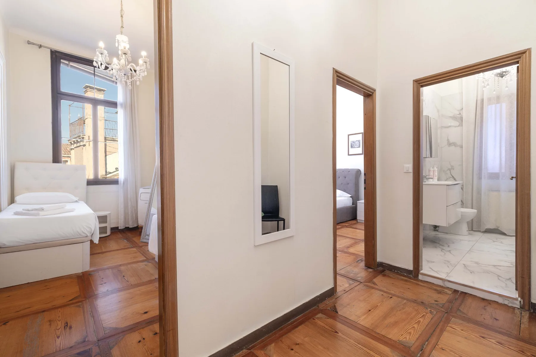 A bright bedroom hallway with doorways to a bedroom and a bathroom.