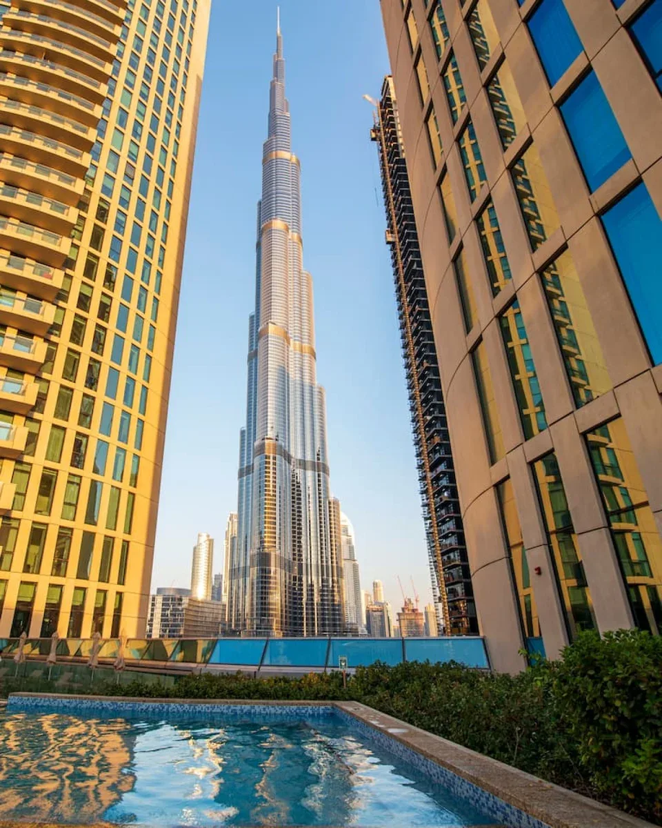 A rooftop pool overlooks the Burj Khalifa between neighboring high-rise buildings.