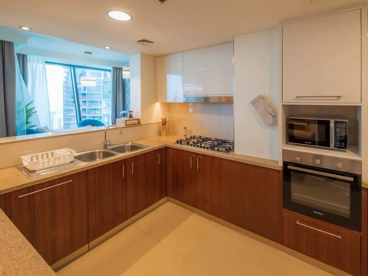 A modern kitchen with wooden cabinets, a sink, and built-in cooking appliances.