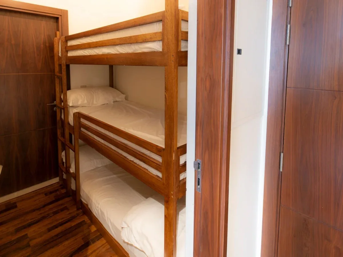 A bunk bed with white bedding stands in a small bedroom.