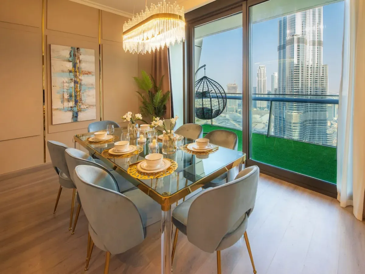 A dining area with a glass table set beside floor-to-ceiling windows.