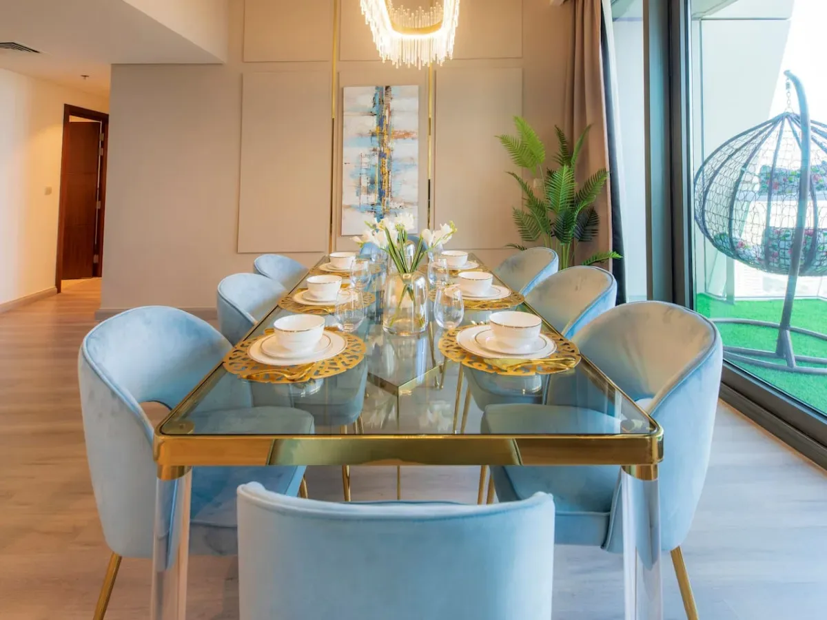 A dining room with a glass table set with plates and flowers.
