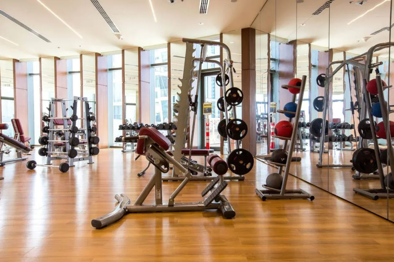 A gym with weight machines and exercise equipment on a wood floor.