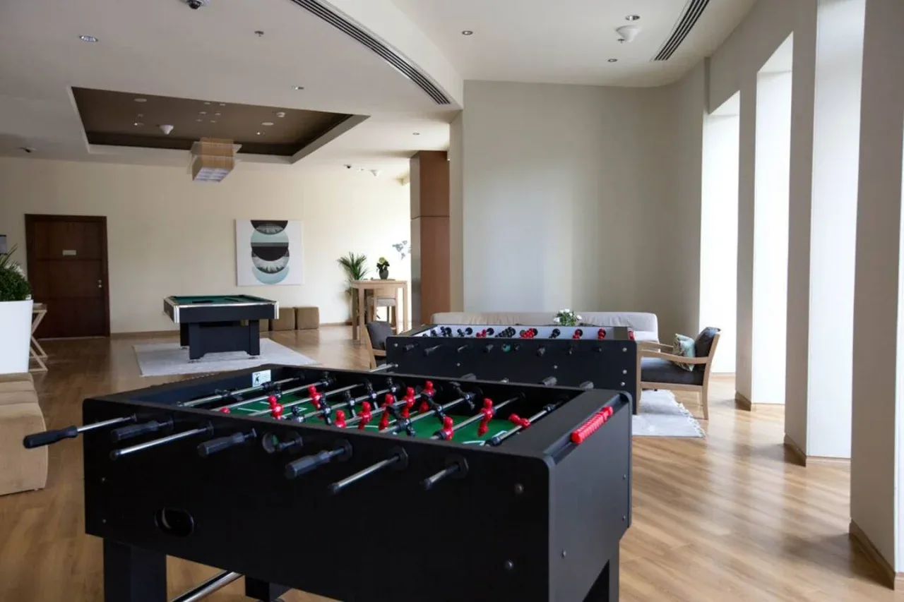 A bright recreation room with two foosball tables and seating.
