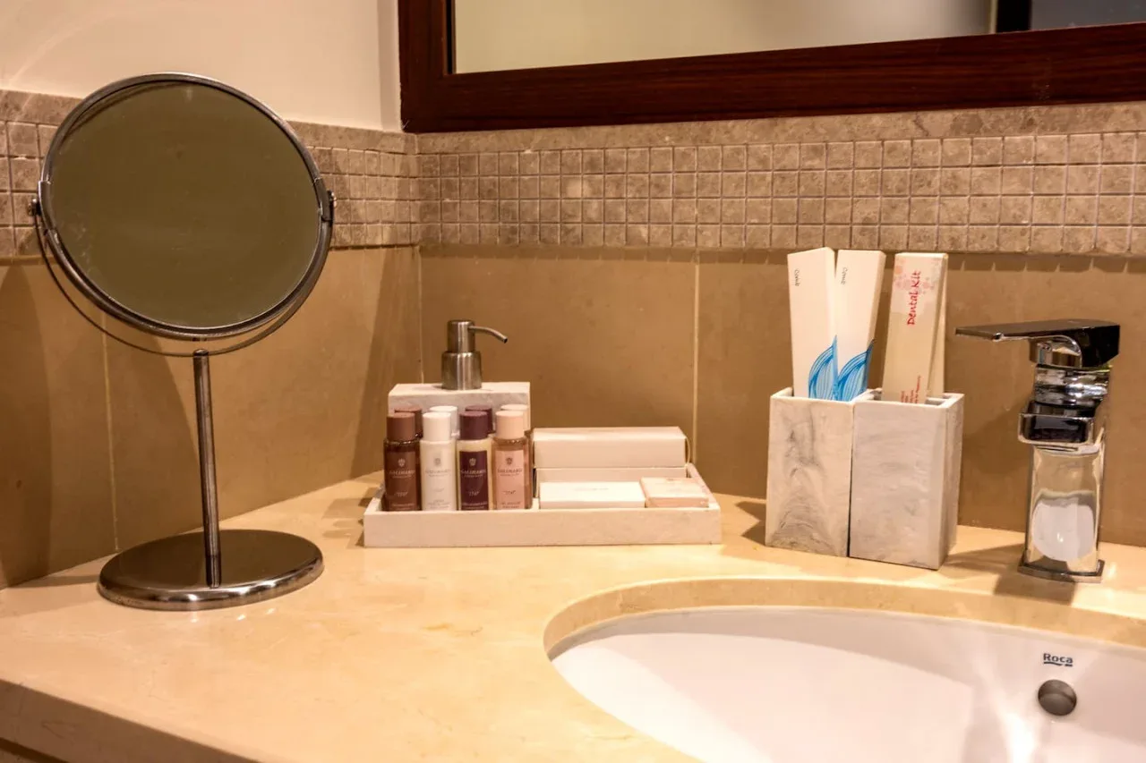 A bathroom vanity with a sink, mirror, and toiletries on the counter.