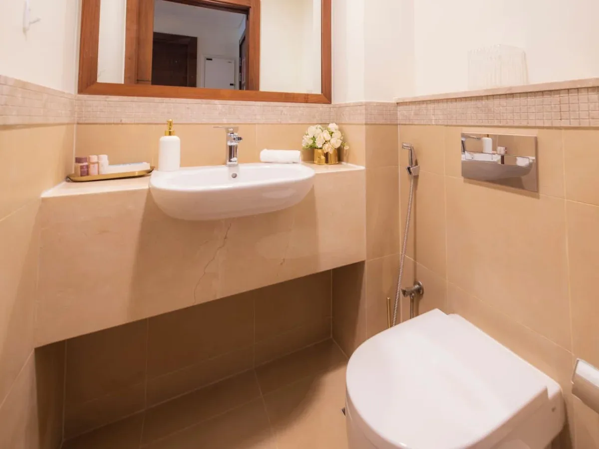 A tiled bathroom with a wall-mounted sink and toilet.