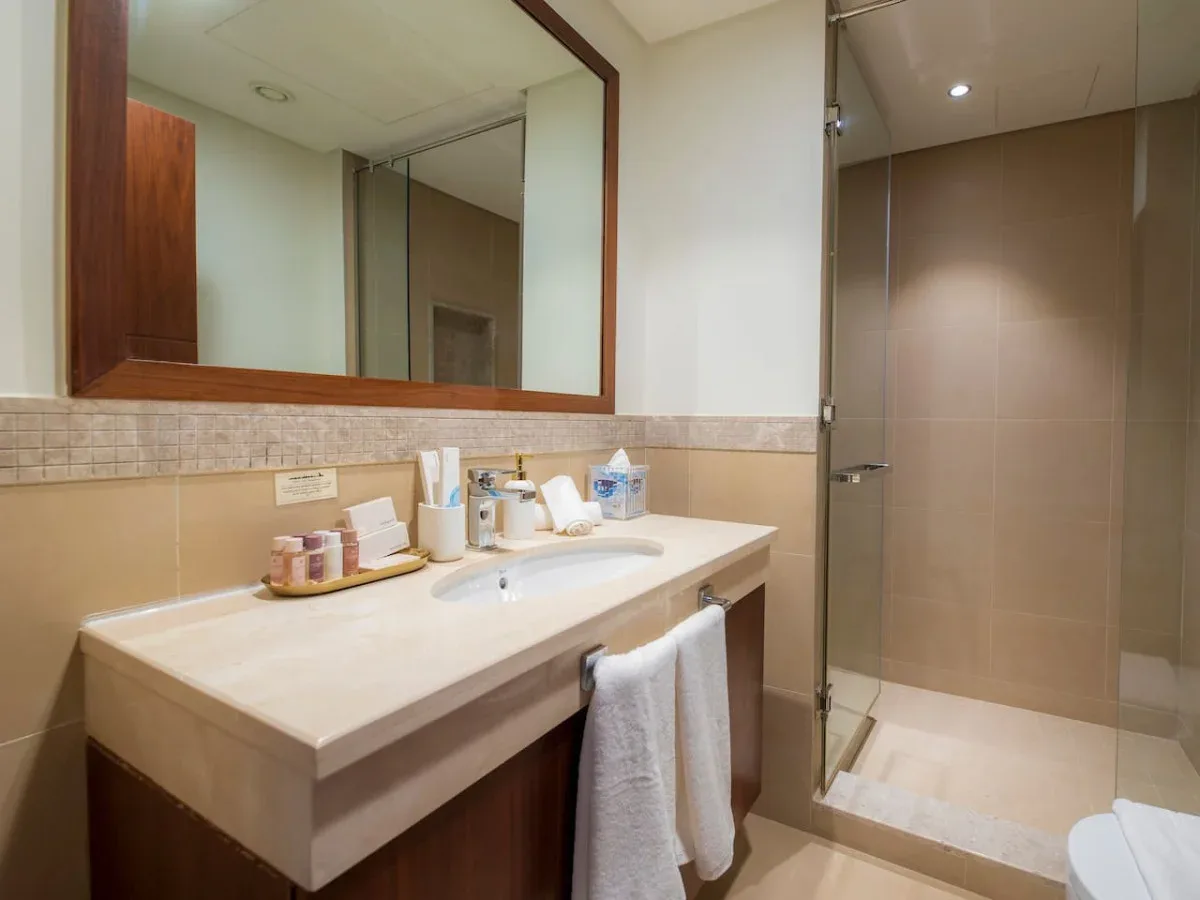 A bathroom vanity with a wide mirror beside a glass shower.