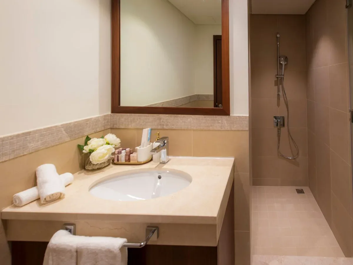 A bathroom vanity with a sink and a shower beside it.