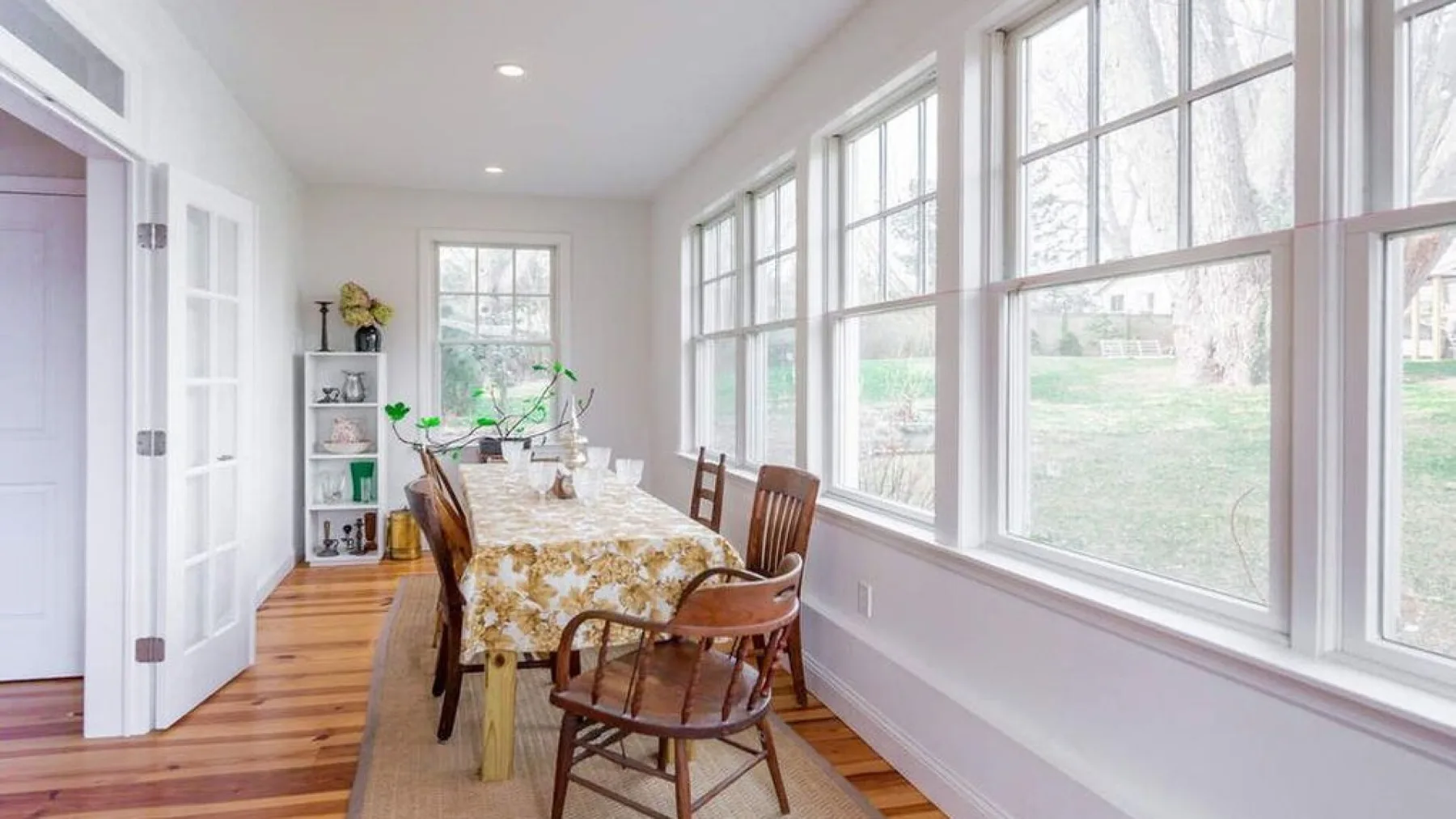 A bright dining room with a table and chairs beside large windows.