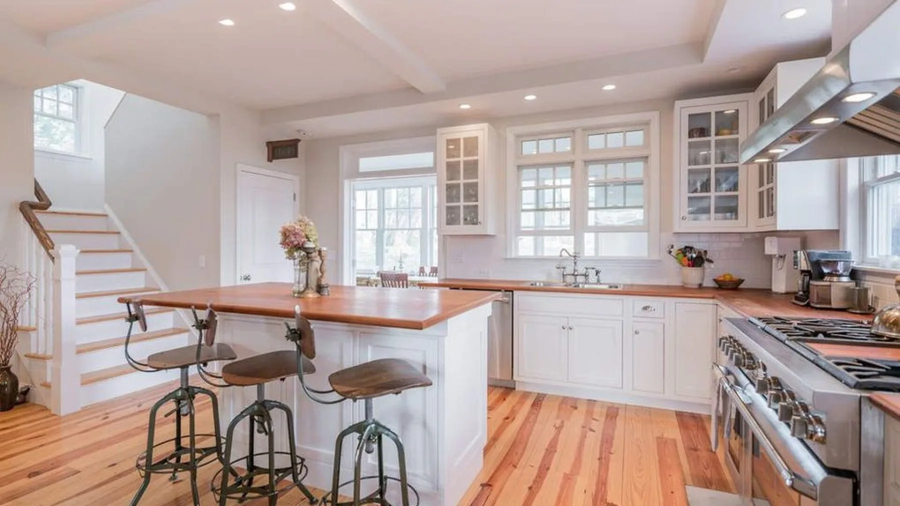 A bright kitchen with white cabinets, a central island, and a stainless steel range.