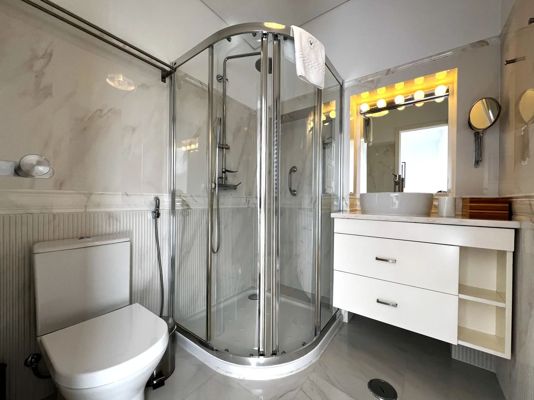 Un baño con ducha curva de cristal, inodoro y lavabo.
