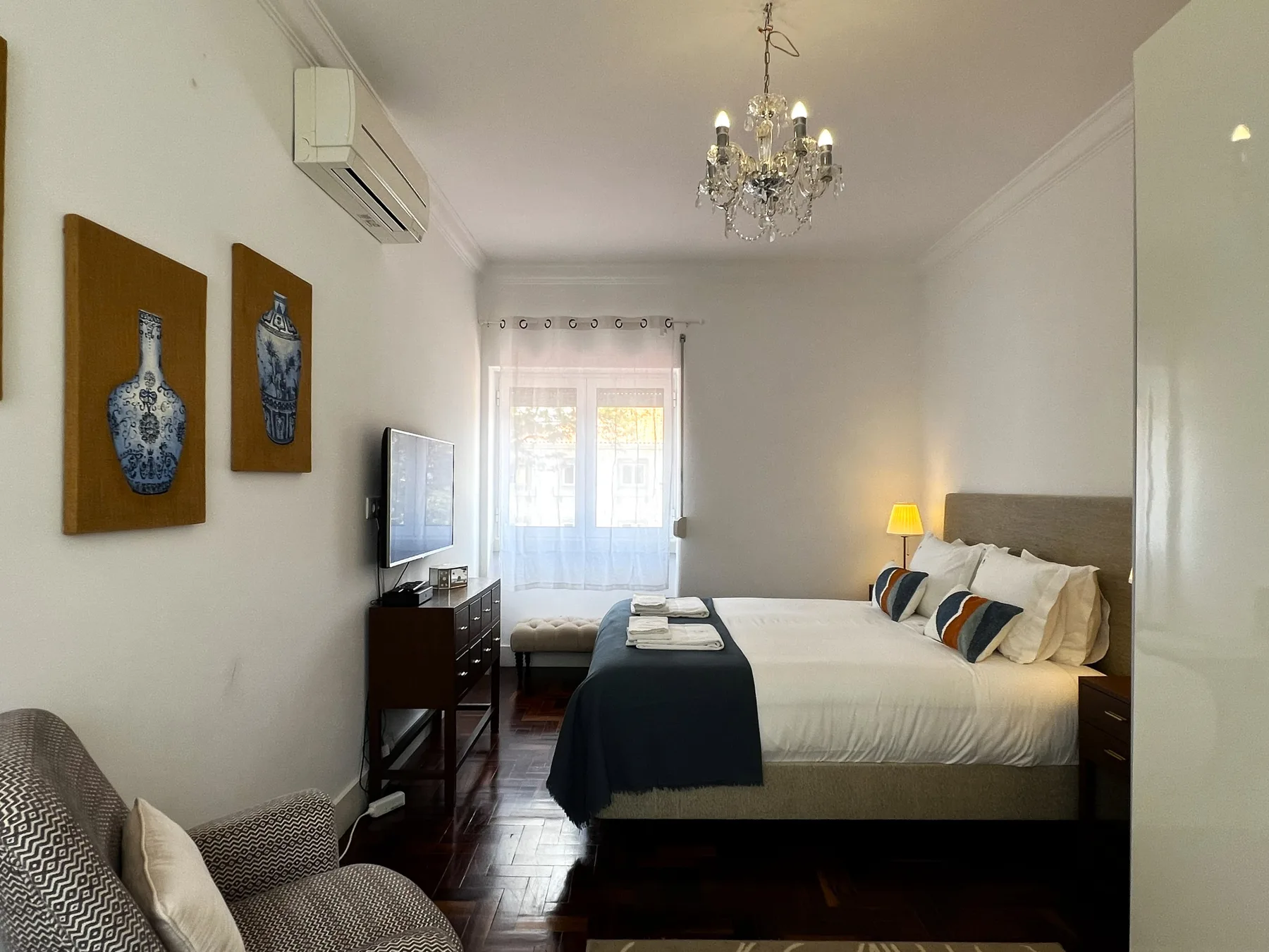 Dormitorio luminoso con una cama, asientos junto a la cama y una ventana.