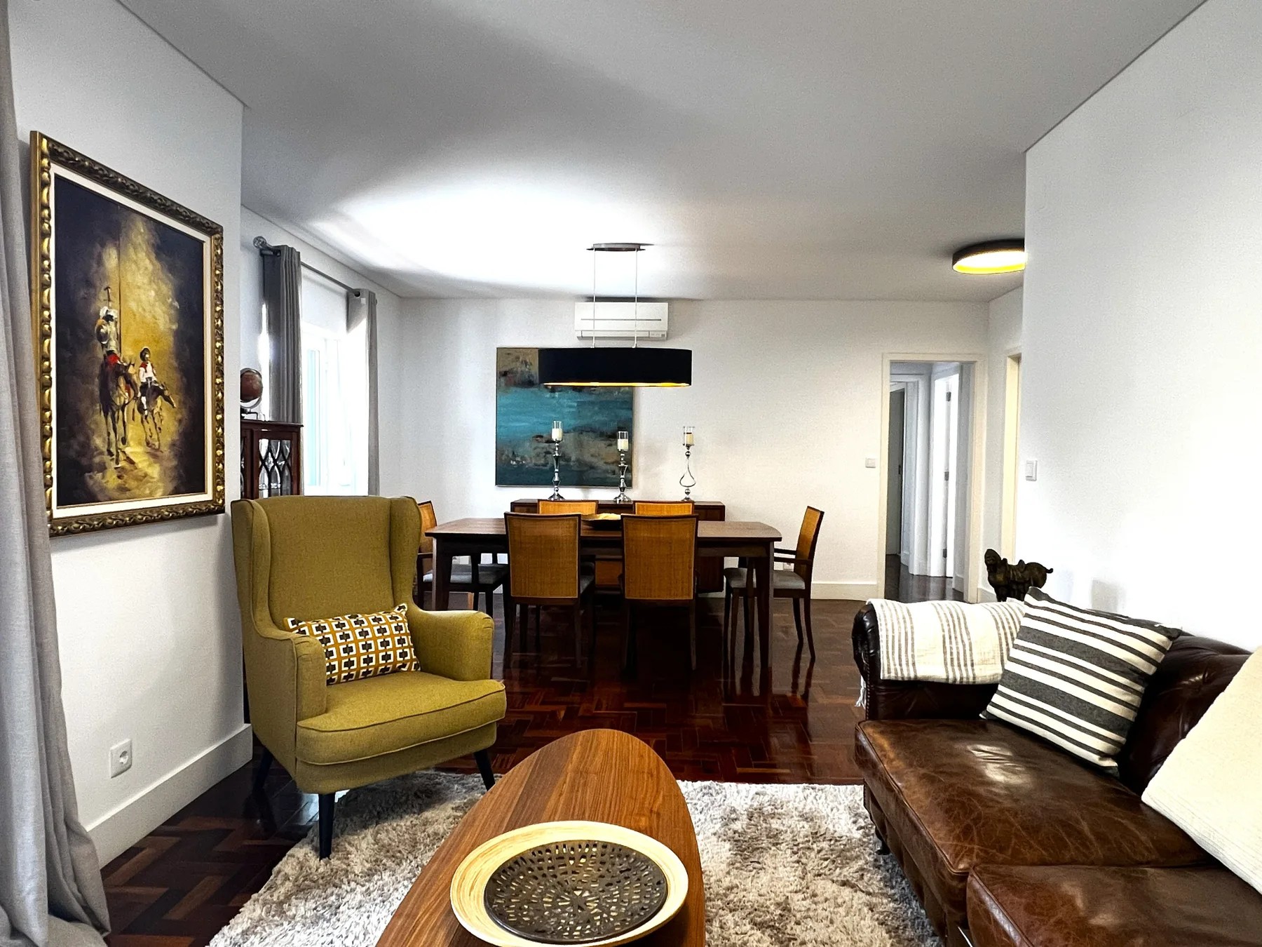 Sala de estar y comedor con un sofá de cuero marrón y una mesa de comedor de madera.