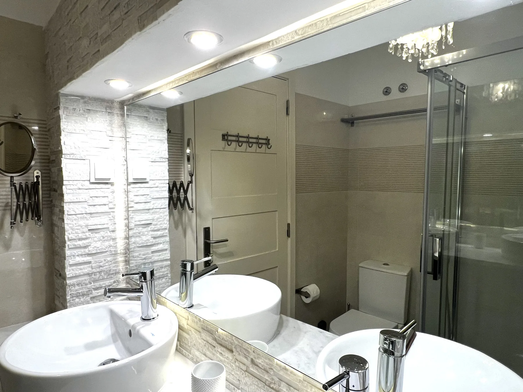 Un baño con dos lavabos, un espejo grande y una ducha de vidrio.