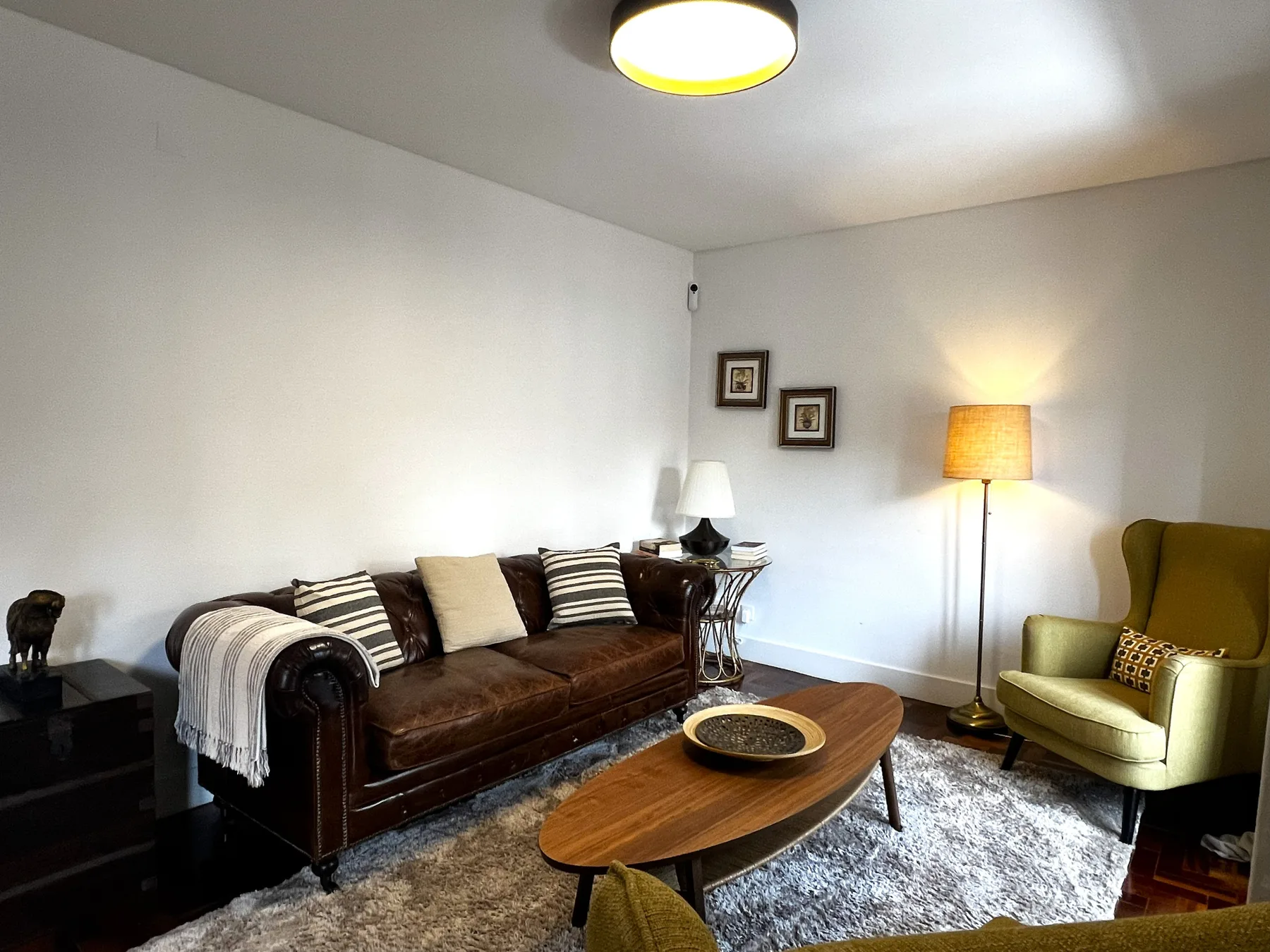 Una sala de estar con un sofá marrón, una mesa de centro y un sillón.