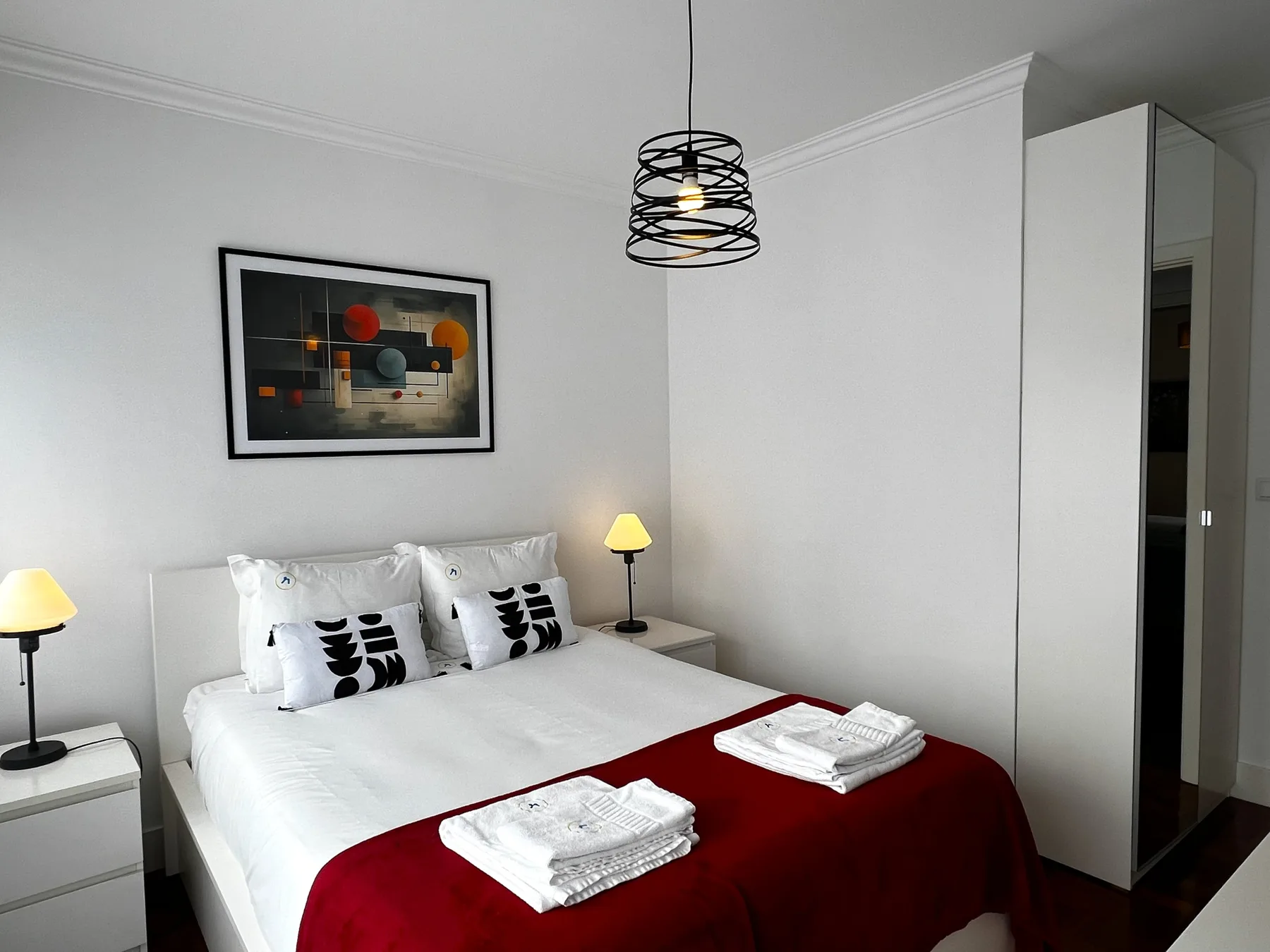 Un dormitorio con una cama bien hecha y una obra enmarcada en la pared.