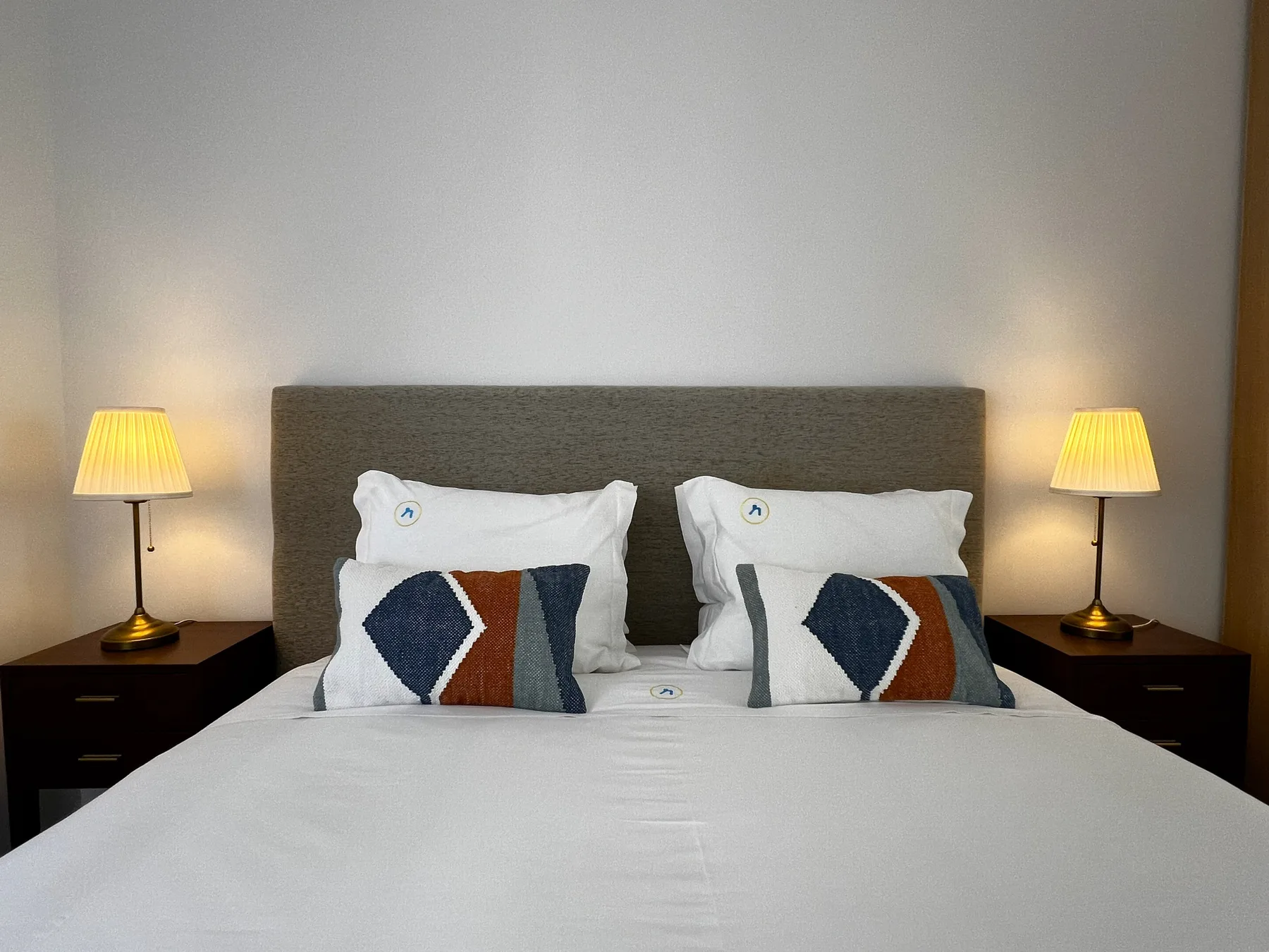 Un dormitorio con una cama bien arreglada y lámparas a juego junto a la cama.