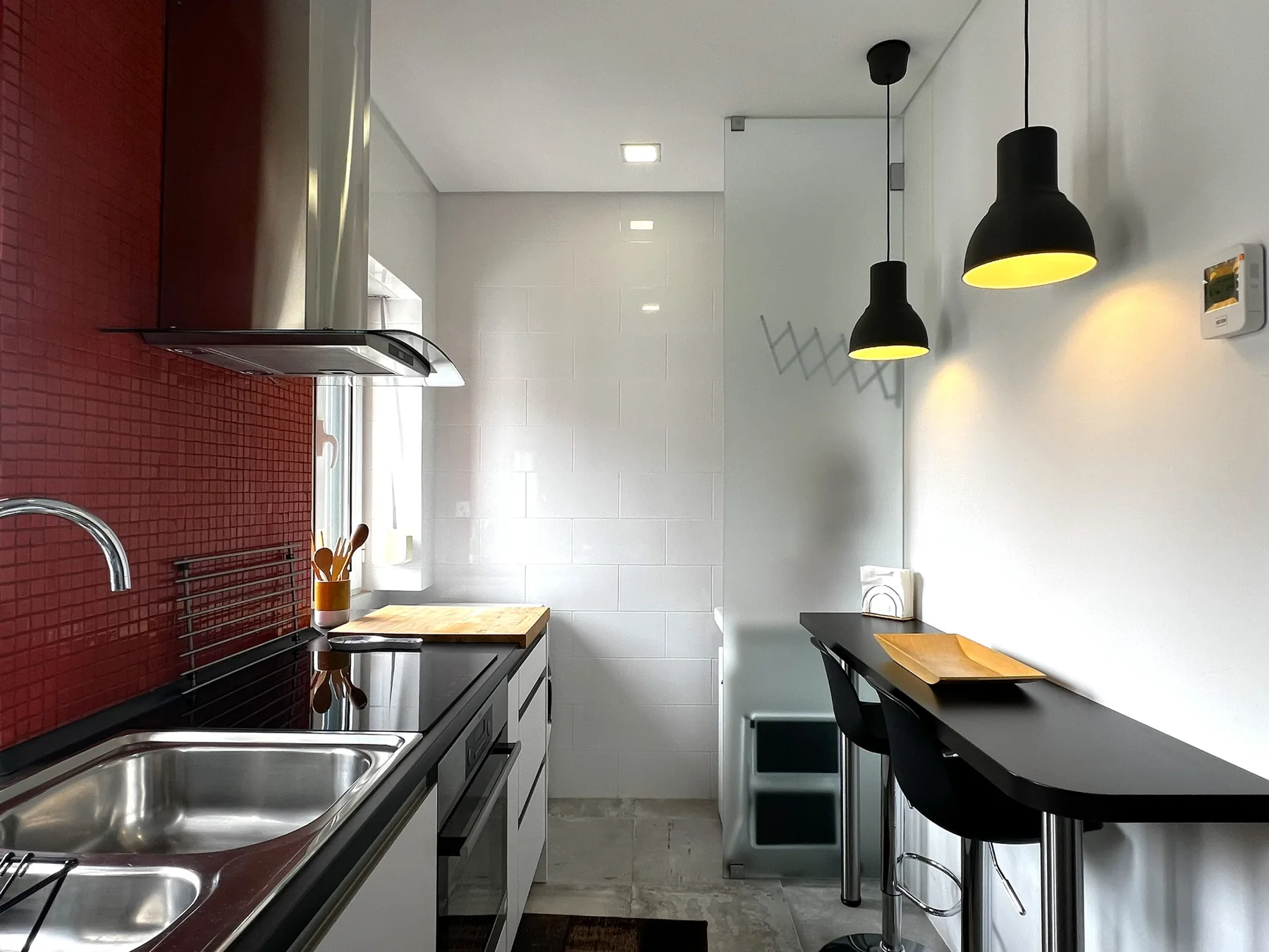 Una cocina moderna con una barra estrecha y lámparas colgantes.